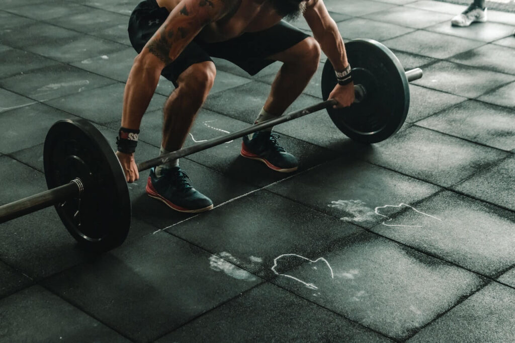 A man picking up a weight bar in a gym.