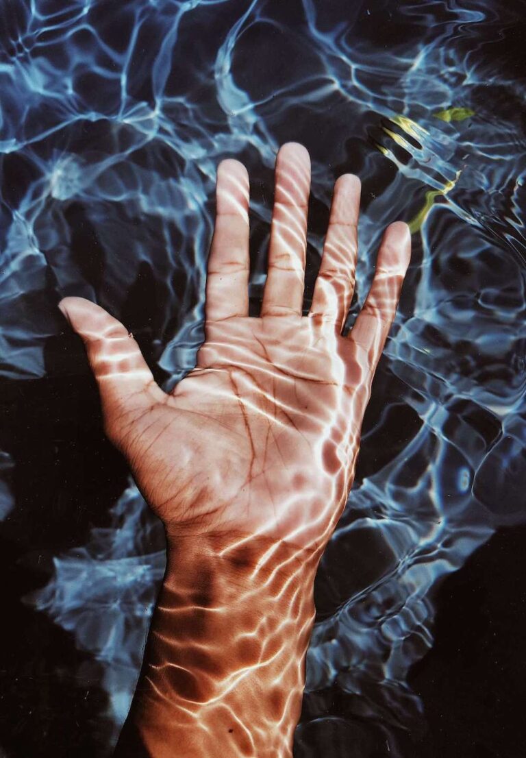 A hand underwater with sunlight creating ripples