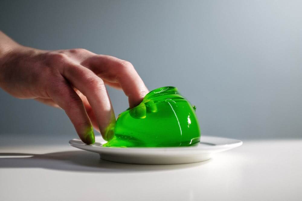 fingers going into green jelly made of water and gelatine