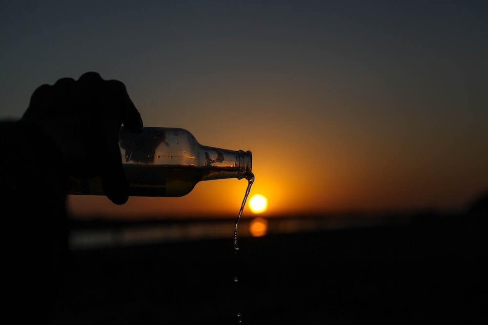 water being poured out of a bottle with the sun setting in the background